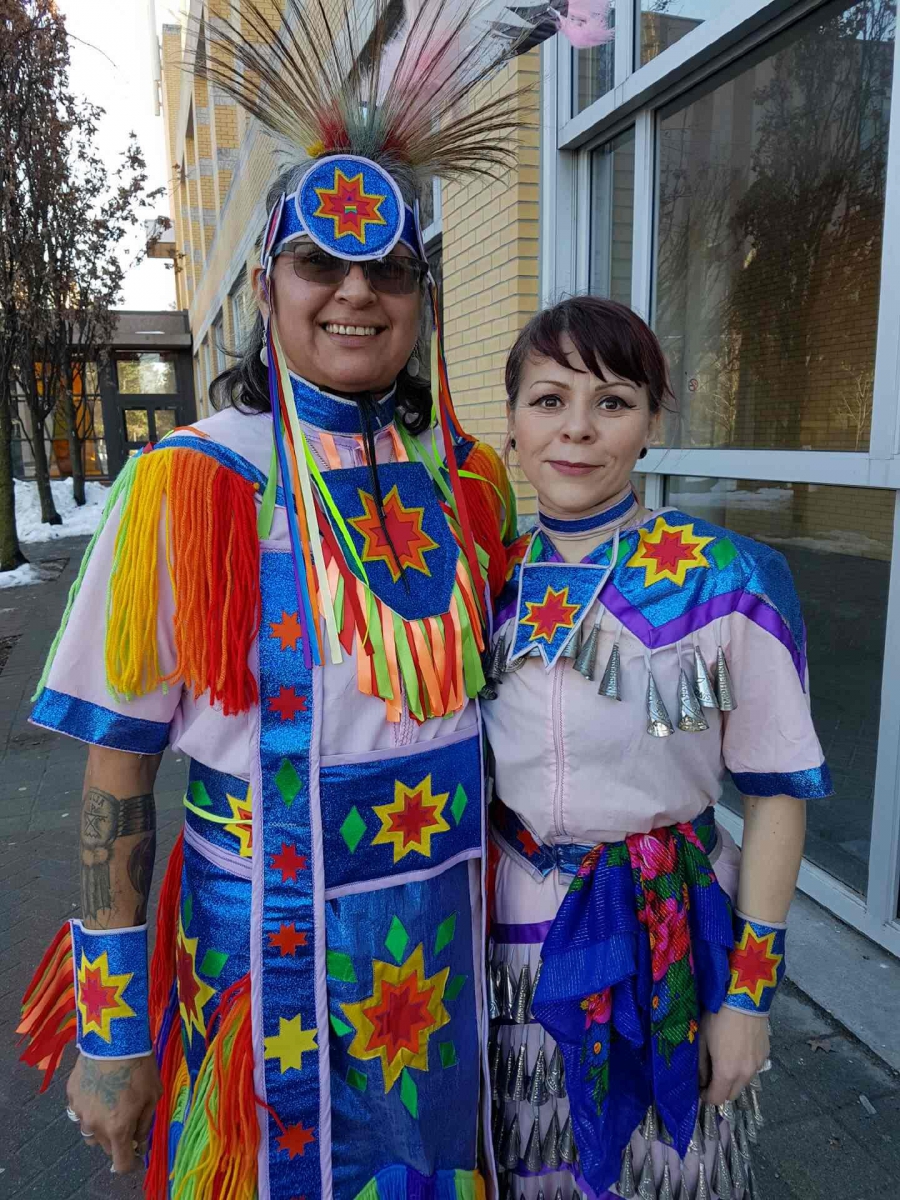 Sue and Marija stand together, smiling, in traditional dress