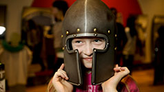 Families play dress-up in the ROM's hands-on galleries. Girl wearing a medieval helmet from a suite of armour.